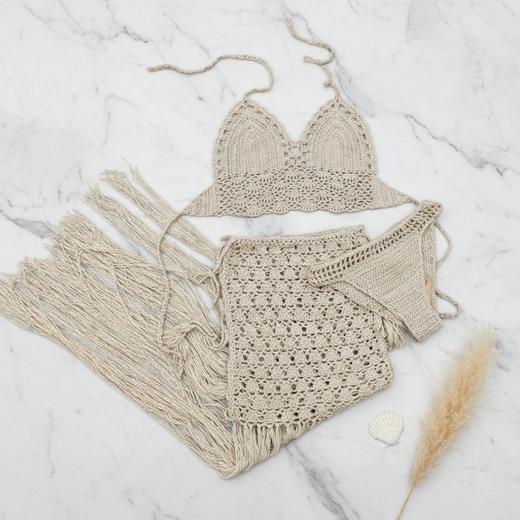 Beige crochet bikini set with tassels on a textured surface.