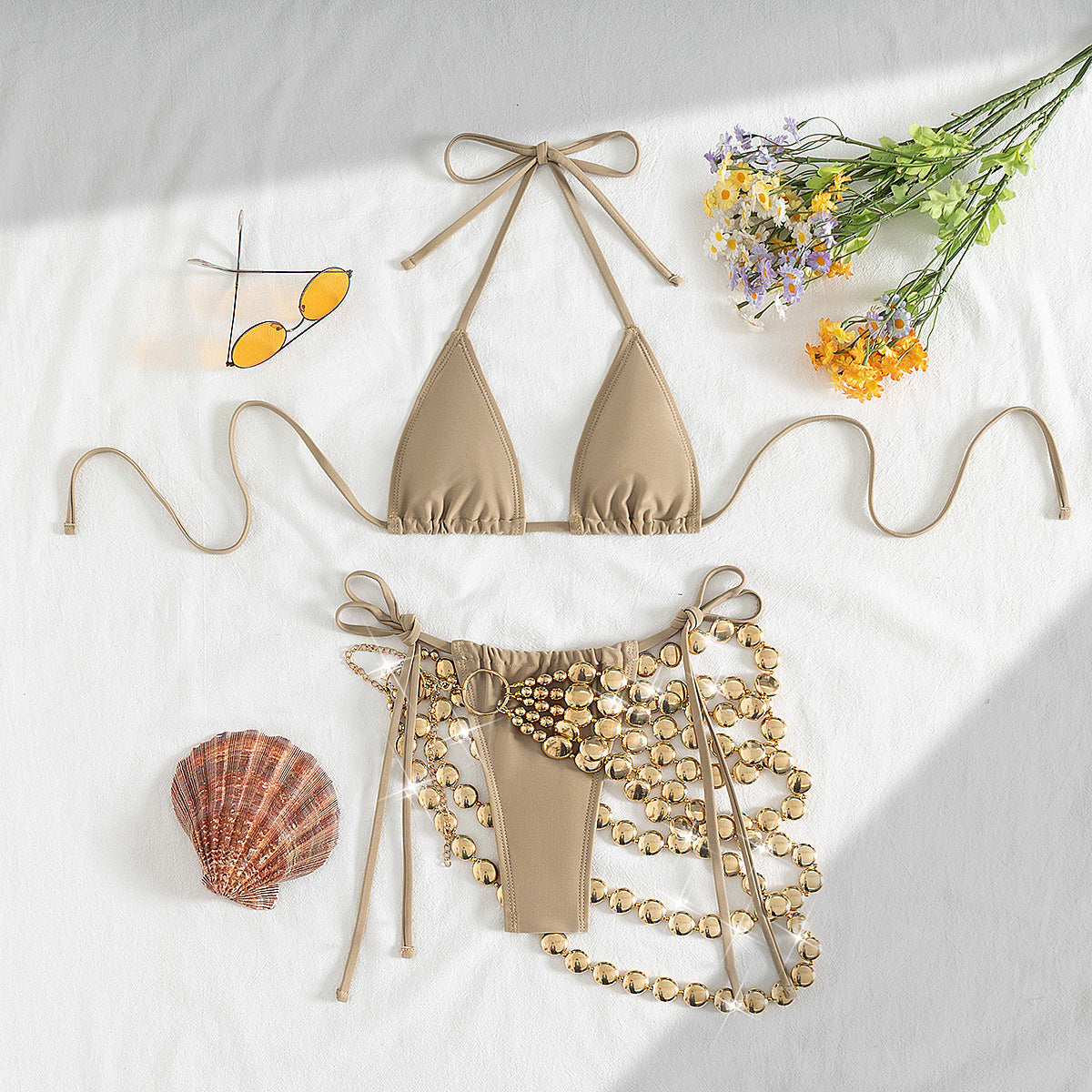 Beige bikini set with decorative elements on a light background