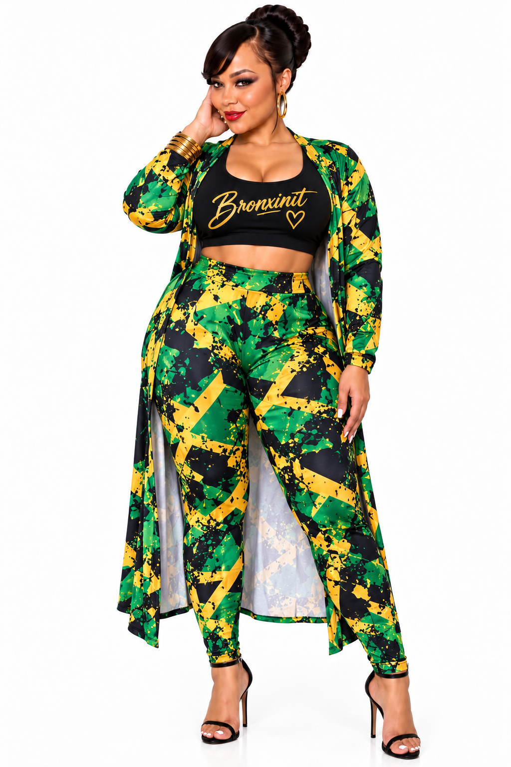 A woman modeling a Jamaica-themed two-piece outfit featuring a green, yellow, and black patterned long-sleeve crop top with 'Brenxinit' printed on the chest, paired with matching high-waisted trousers and a matching open-front long cardigan.