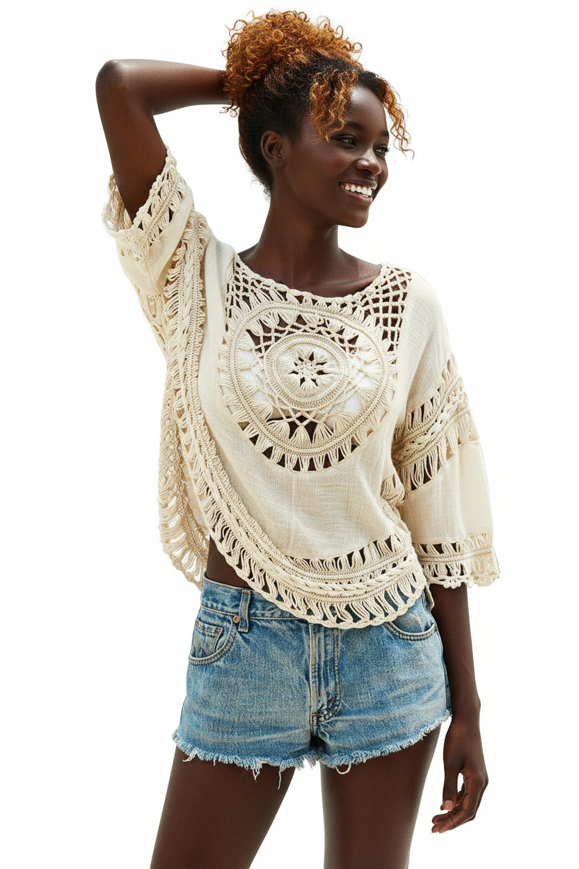 A woman wearing a beige and white bohemian blouse with a thin outer cutout and blue denim shorts.