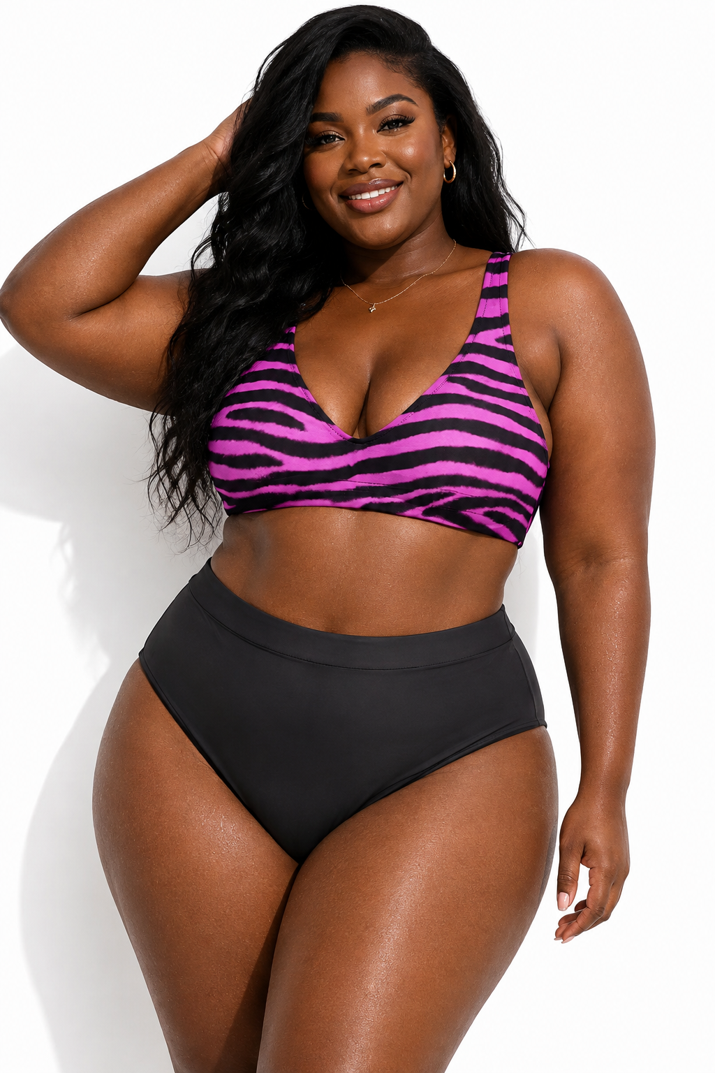 A plus-size woman modeling a two-piece swimsuit with a pink and black zebra-print bikini top and solid black high-waisted bottoms, posed against a clean white background.