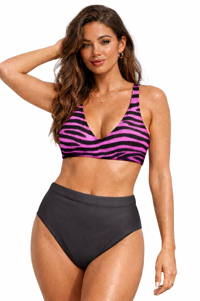 A woman modeling a two-piece bikini set against a plain white background. The bikini top features a vibrant pink and black zebra stripe pattern, while the high-waisted bikini bottom is solid black.
