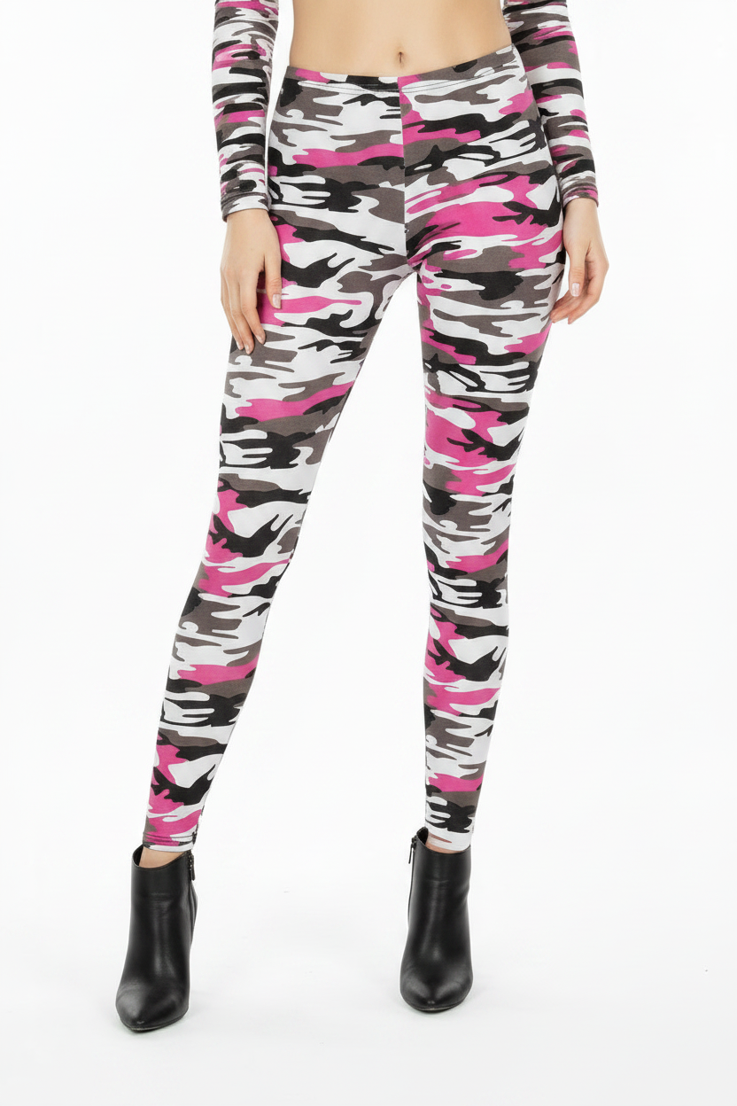 A woman modeling a matching two-piece activewear set featuring a pink, black, and white camouflage pattern, consisting of a long-sleeve crop top and high-waisted leggings, paired with black ankle boots against a plain white studio background.
