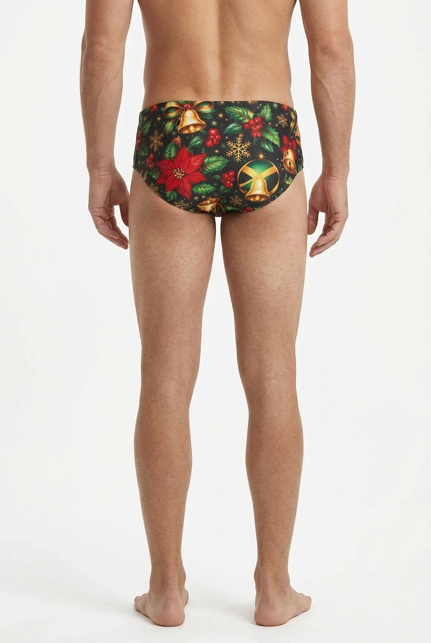 Rear view of a man wearing men's swim briefs with a festive Christmas print featuring red poinsettias, green holly leaves, gold bells, and red berries on a black background, set against a plain white studio background.