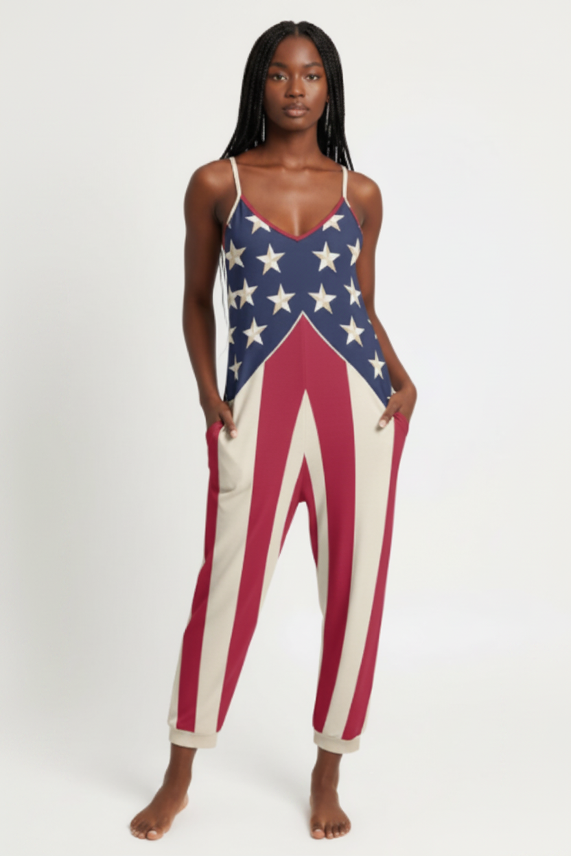 A woman modeling a sleeveless jumpsuit with an American flag pattern, featuring white stars on a blue top section and red and white stripes on the pants, set against a plain white studio background.