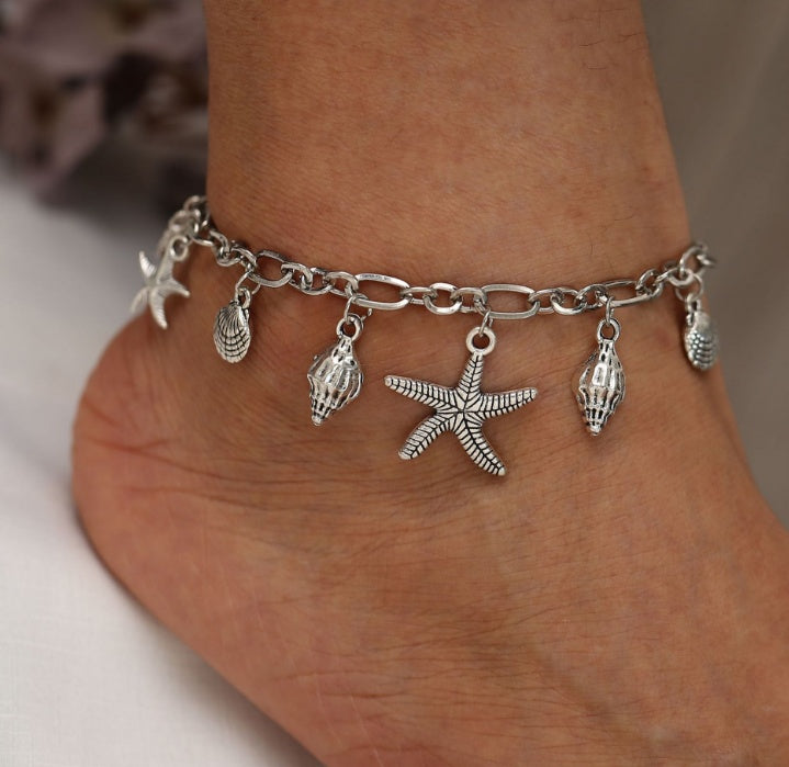 A silver-colored anklet with Boho Turtle Pendant design, displayed on a woman's ankle.