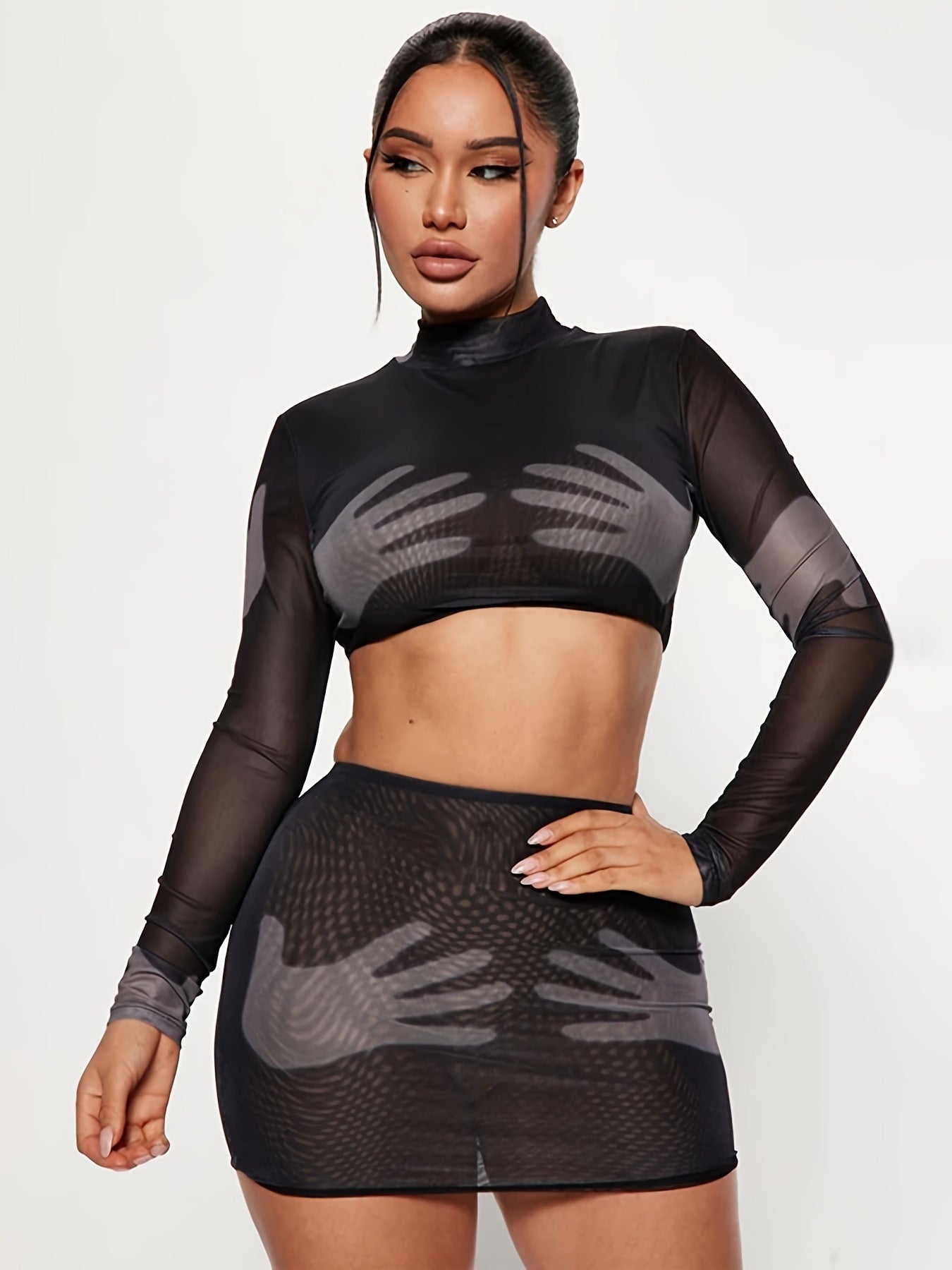 Woman wearing a black mesh outfit with long sleeves and a skirt on a white background
